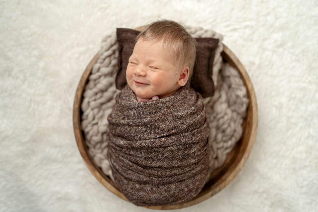 Smiling baby wrapped in a bowl in Eldersburg, MD Newborn Photography Session