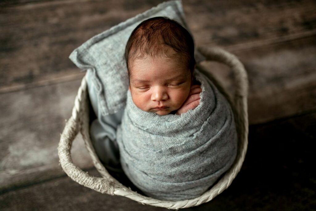 Baby boy wrapped in blue in a white basket during Newborn Photo Session in Reisterstown, MD