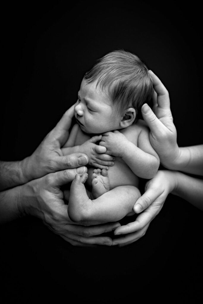 Baltimore Newborn Photography Session features black and white image of baby sleeping in parents hands