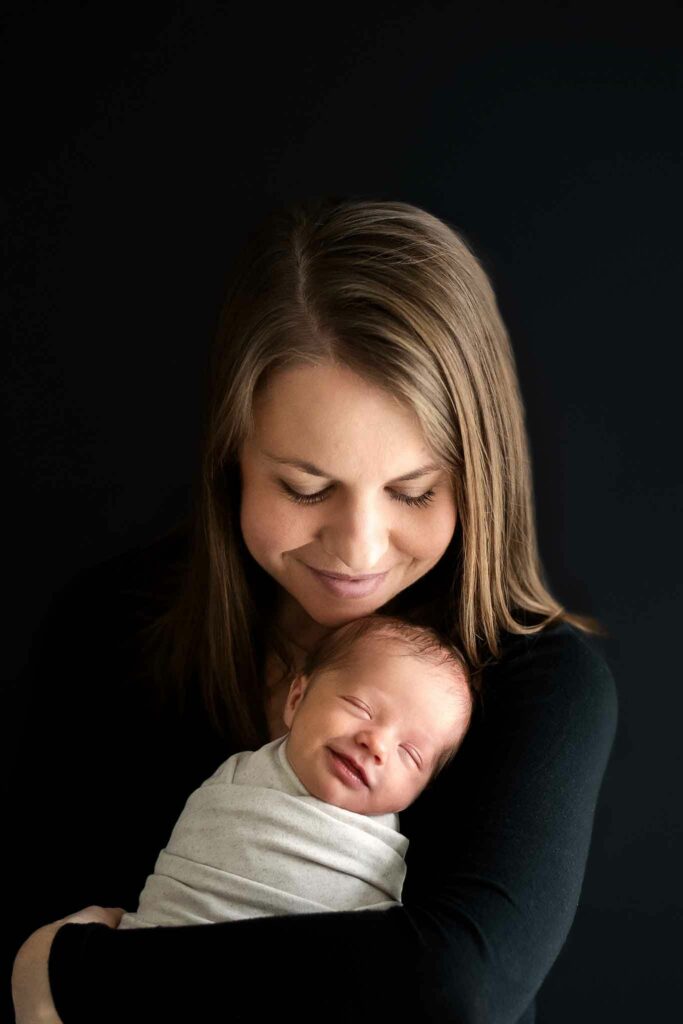 Mom holding smiling baby during Ellicott City Newborn Photo Session