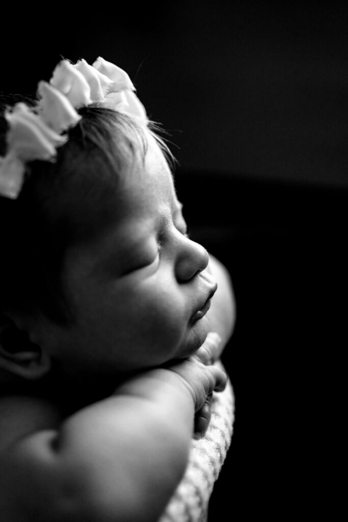 Black and white image of newborn resting chin on hands in Ellicott City In-Home Photography Session