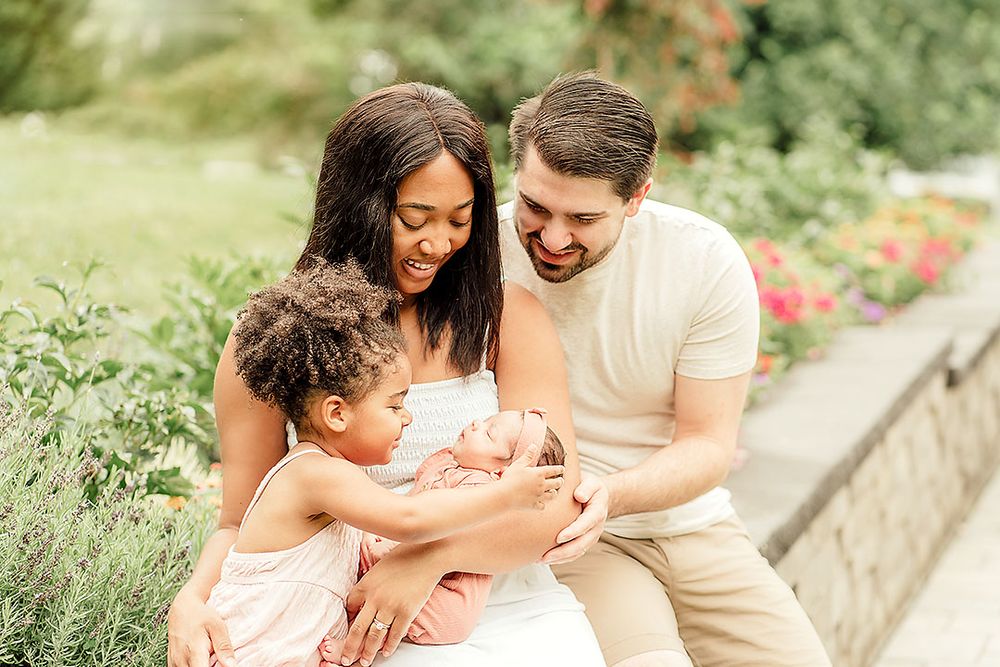 Ellicott City family in their back yard flower garden admiring their new baby during their Lifestyle Photography Session