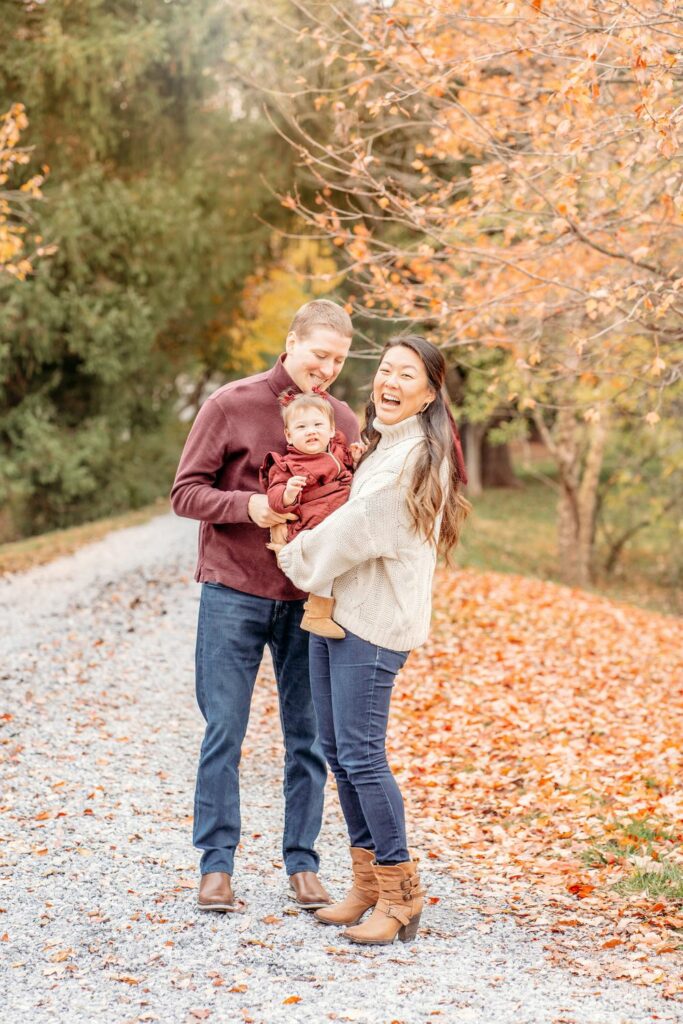 Fall family photo session with mom and dad holding their baby and laughing at the Howard County Conservancy