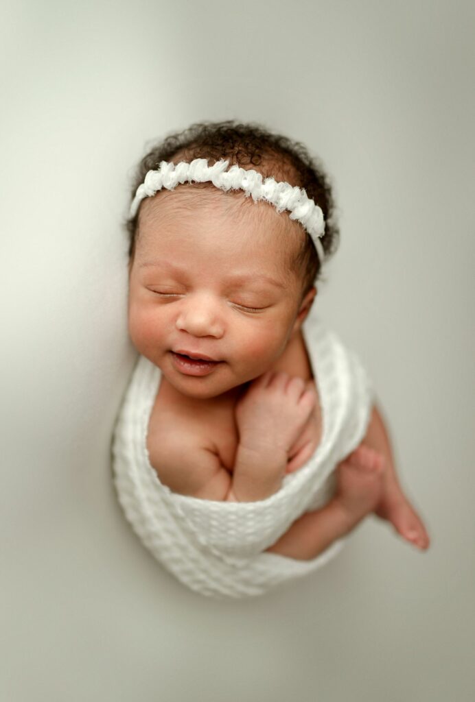 smiling baby in whites during in-home newborn photography session in Howard County
