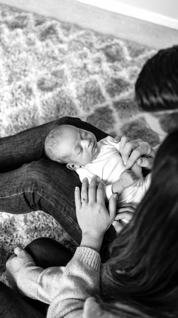 Black and white image of baby sleeping in dads lap during a Lifestyle Photography Session