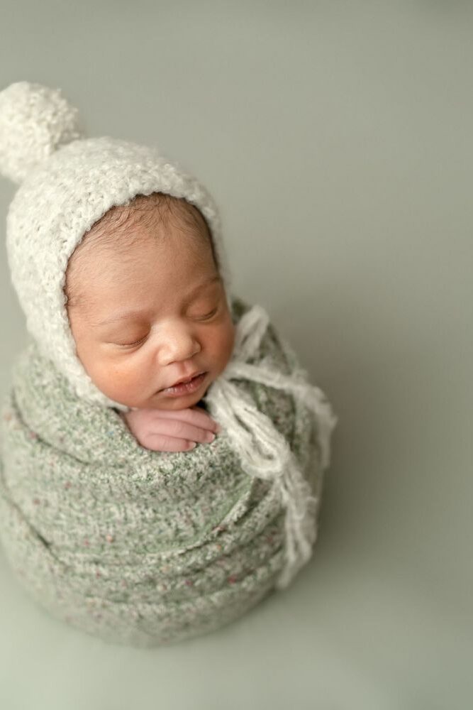 Baby wrapped in green with pom hat in Clarksville MD Home Newborn Photo Session
