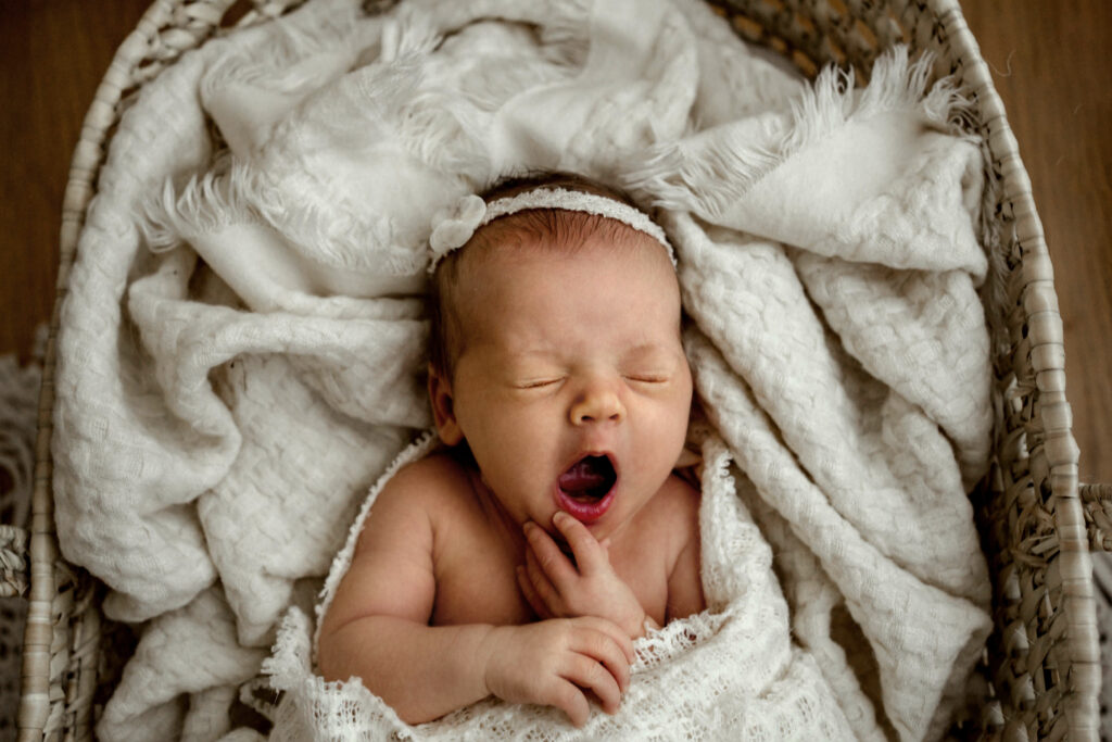 Baby yawning in Bassinet in her Ellicott City, MD living room during her Lifestyle Newborn Photo Session