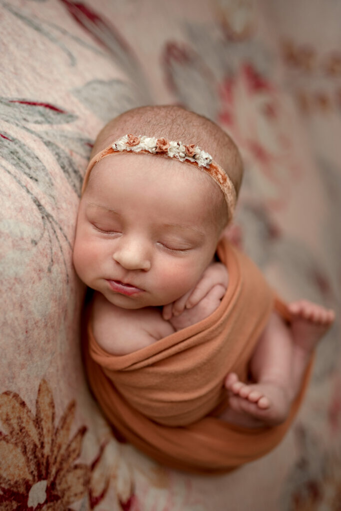 newborn posed on floral backdrop