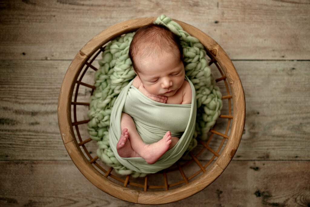 Columbia MD Newborn Photography in-home session featuring baby boy posed on greens in bowl