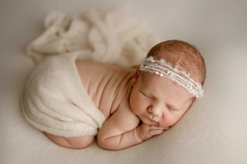 Baby girl posed on creams during newborn photo session in Baltimore, MD