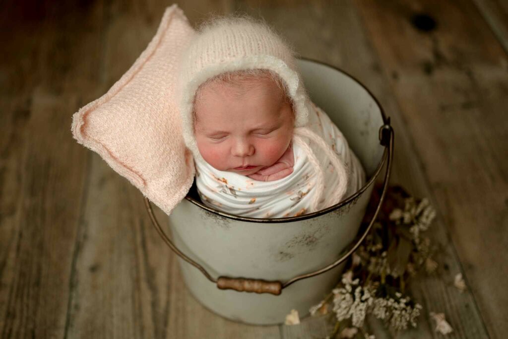 Newborn wrapped in a bucket for mini session in Baltimore MD