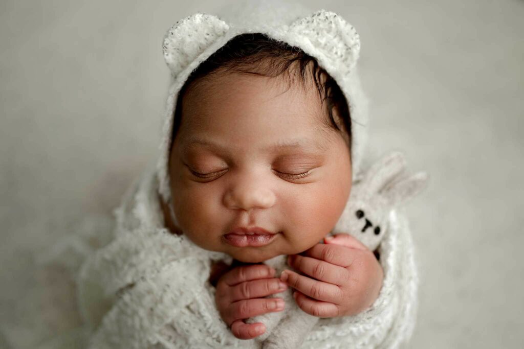 Newborn wrapped with a bear bonnet and bunny during mini session in Baltimore MD