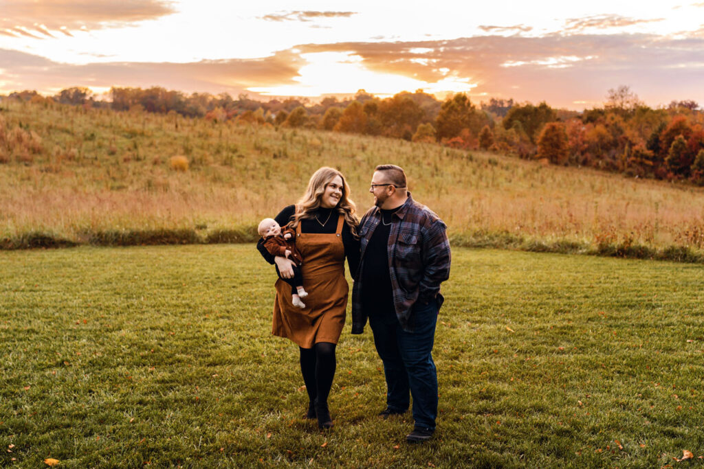 A family walking through a field with a perfect glowing sunset directly behind them in Howard County MD