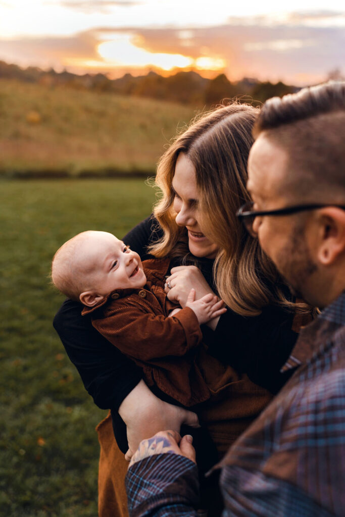 Mom and dad snuggle their baby boy in a gorgeous field at sunset in Howard County MD