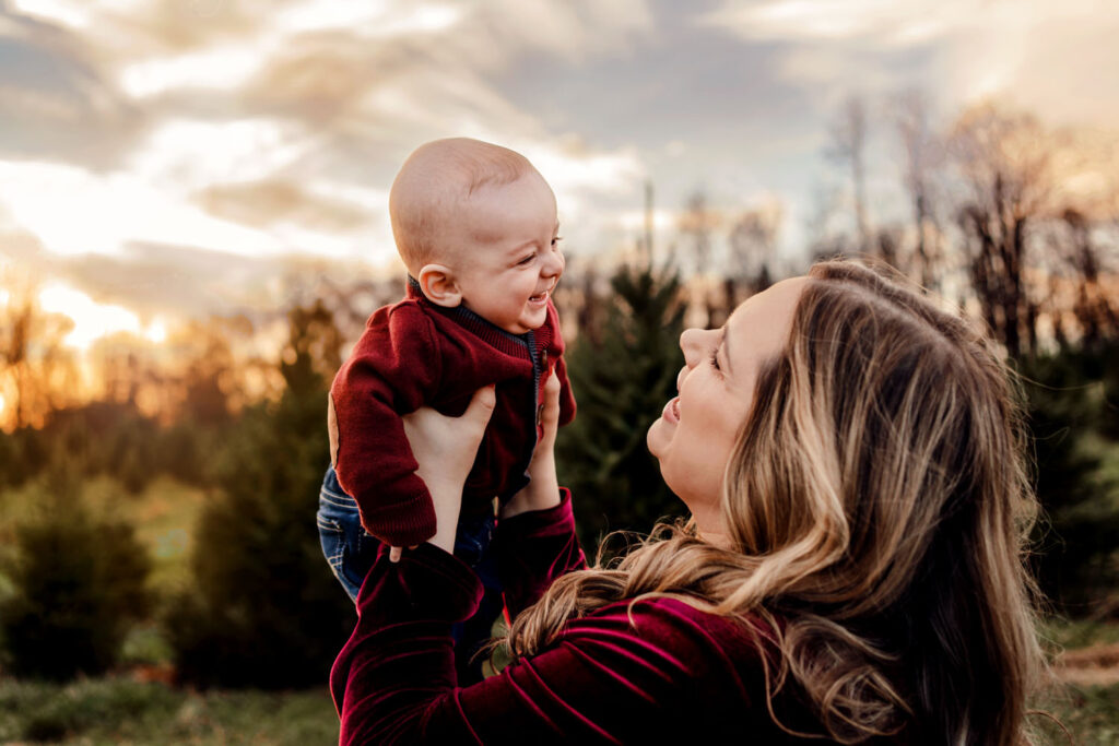 Baby smiles at his mama at sunset during their tree farm photo session in Howard County, MD