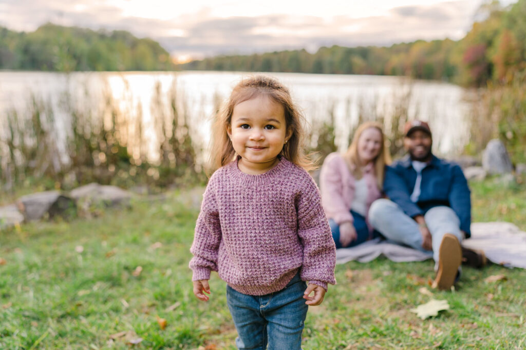 Adorable toddler in front of her parents and a picturesque lake sunset at Centennial Park in Ellicott City MD