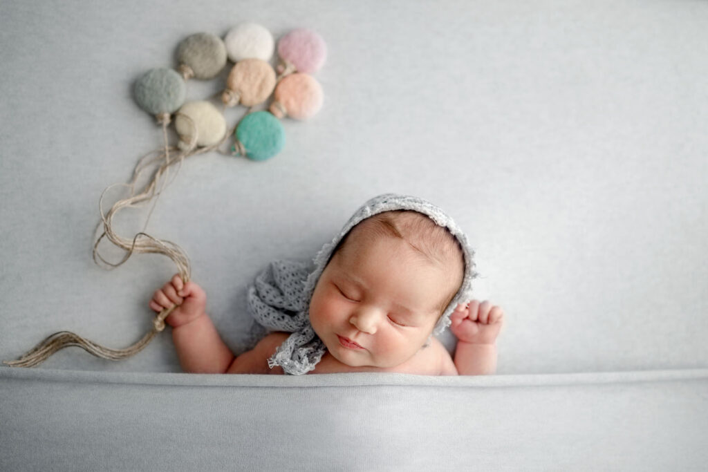 Ellicott City rainbow baby holding balloons during her newborn photo session