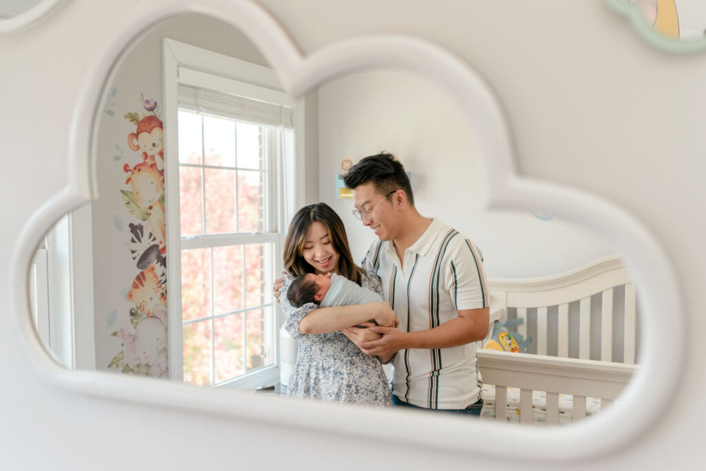 A cloud mirror reflects parents adoring their newborn during their Lifestyle Newborn Session in Fulton, MD