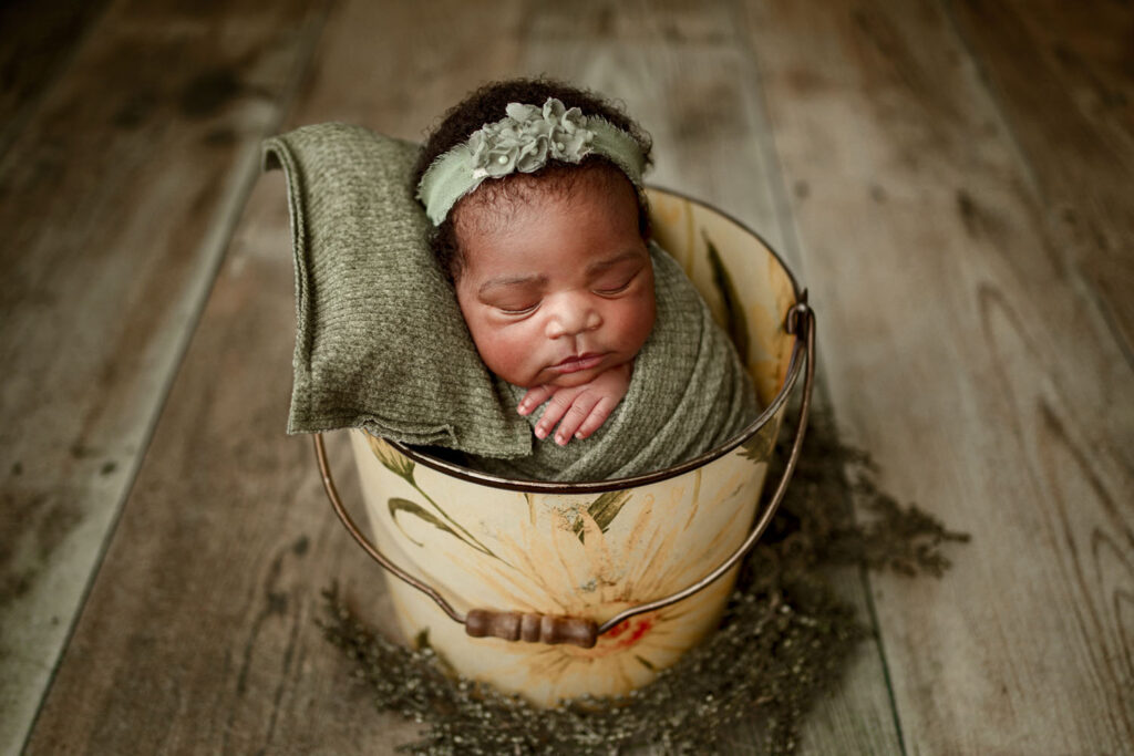 Baby sleeping in a yellow flowered bucket