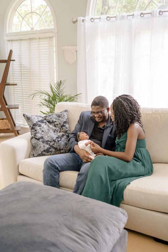 Parents admire their newborn baby during their Lifestyle photo session in their living room
